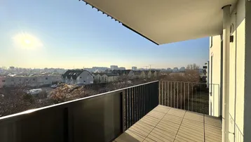 Heller Balkon mit Fliesenboden und weitem Blick über die Stadtlandschaft bei Sonnenschein.