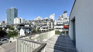Große Holzterrasse mit modernem Geländer und weitem Blick auf die Stadtlandschaft.