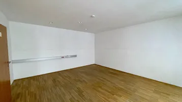Leerer Büroraum mit hellem Holzparkett und weiß gestrichenen Wänden, bereit zur individuellen Gestaltung.