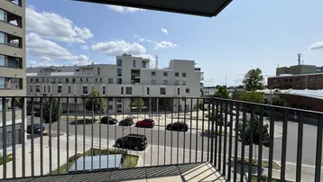 Blick vom Balkon auf moderne Wohngebäude und die umliegende Stadtlandschaft unter blauem Himmel.
