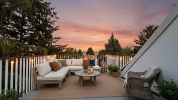 Geräumige Dachterrasse mit gemütlicher Lounge-Möblierung und stimmungsvoller Beleuchtung bei Sonnenuntergang.