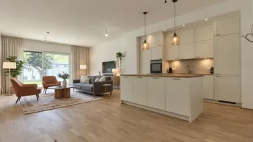 Heller offener Wohnbereich mit integrierter Küche, Holzboden und Zugang zum Garten.