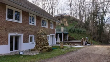 Backansicht des Hauses mit Ziegelmauerwerk, weißem Sockel und einem Außenbereich mit Steindekoration.