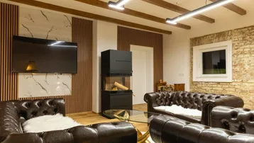 Wohnzimmer mit modernem Kaminofen, Flachbildfernseher und Ledersofas.