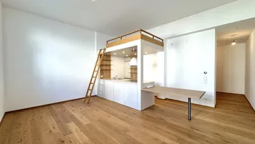 Helles offenes Wohnzimmer mit integrierter Küchenzeile und Hochbett in einem modernen Apartment.
