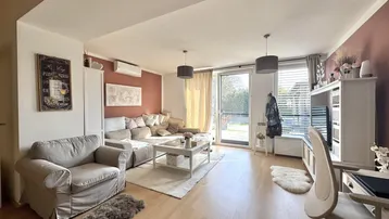 Helles Wohnzimmer mit beigefarbenem Sofa, Holzboden und Zugang zur Terrasse.