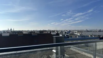 Panoramablick über die Stadt von einer Dachterrasse mit moderner Glasbrüstung und weitem Horizont.