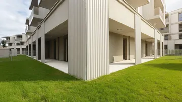 Moderne Gebäudefassade mit großzügiger Terrasse und gepflegtem Rasenbereich.