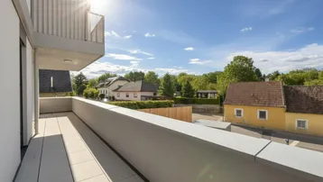 Sonniger Balkon mit Fliesenboden und Blick auf die umliegende Wohngegend und viel Grün.