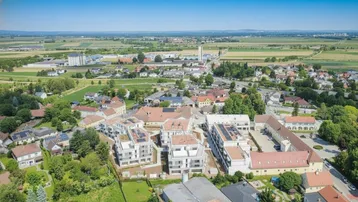 Luftaufnahme einer modernen Wohnsiedlung umgeben von grüner Landschaft und Feldern.