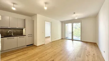 Lichtdurchfluteter Wohnbereich mit Holzboden und Zugang zu einem französischen Balkon.