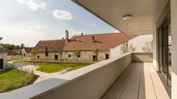 Geräumiger Balkon mit Fliesenboden und Blick auf die umliegende Landschaft und alte Gebäude.