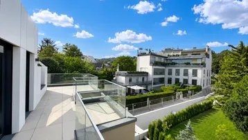 Große Dachterrasse mit Glasgeländer und weitem Blick über die umliegende Bebauung und viel Grün.