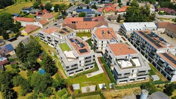 Luftaufnahme einer modernen Wohnanlage mit mehreren Gebäuden und Gründächern in ländlicher Umgebung.