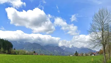 Malerischer Blick auf die Berge, grüne Wiesen und den blauen Himmel.