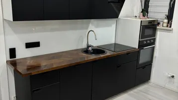 Moderne schwarze Küche mit integrierten Geräten, Spüle und Induktionskochfeld.