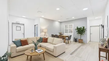 Helles, offen gestaltetes Wohn- und Esszimmer mit beigem Sofa und Holzboden.