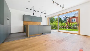 Heller offener Wohn- und Essbereich mit moderner Küche, Holzboden und Zugang zum Garten.