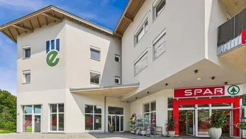 Ansicht des modernen Geschäftsgebäudes mit großen Schaufenstern und dem Eingangsbereich eines Supermarktes.