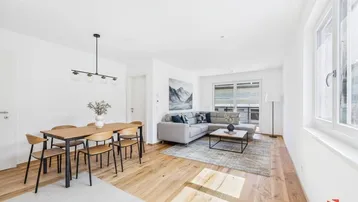 Helles, offenes Wohn-Esszimmer mit modernem Design, Holzboden und Zugang zu einem Balkon.