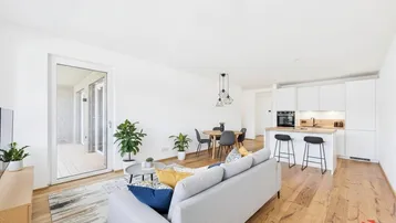 Helles, offenes Wohnzimmer mit integrierter Küche, Essbereich und Zugang zum Balkon.