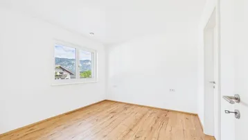 Helles Schlafzimmer mit Holzboden und Bergblick durch das Fenster.