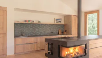 Moderne Holzküche mit integriertem Kamin und geometrischen Fliesen, schafft eine gemütliche Atmosphäre.