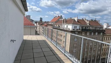 Geräumige Dachterrasse mit Fliesenboden und weitem Blick über die Stadt unter blauem Himmel.