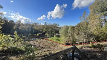 Weitläufiges Grundstück mit natürlicher Vegetation und markierter Grenze unter blauem Himmel.