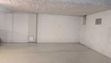 Leerer Parkplatz in einer Tiefgarage mit Betonwänden und -boden.