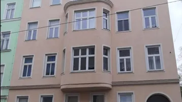 Ansicht der Gebäudefassade mit mehreren Fenstern und einem Erker in einer städtischen Umgebung.
