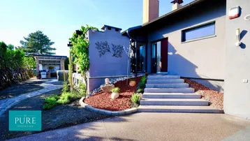 Moderne Hausfassade mit gepflegtem Vorgarten und Zufahrt zum Eingangsbereich.
