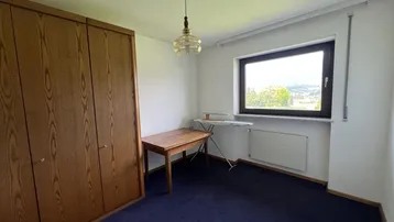 Schlafzimmer mit großem Einbauschrank, Teppichboden und Fenster mit Weitblick.