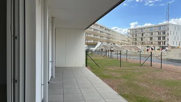 Geflieste Terrasse mit Blick auf die umliegende Neubausiedlung unter blauem Himmel.