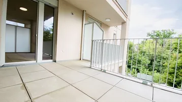 Geräumiger Balkon mit Fliesenboden und Blick ins Grüne, ideal für entspannte Stunden im Freien.
