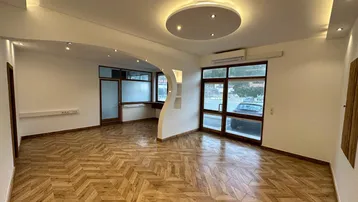 Geräumiger, heller Wohnbereich mit modernem Parkettboden, großen Fenstern und indirekter Deckenbeleuchtung.