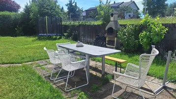 Gepflegter Garten mit Essbereich, Grill und Trampolin, ideal für Familienaktivitäten im Freien.