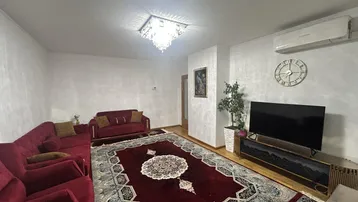 Geräumiges Wohnzimmer mit rotem Sofa, Teppich, Klimaanlage und einem modernen Kronleuchter.