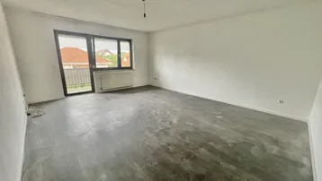 Helles, unmöbliertes Zimmer mit Zugang zu einem Balkon und Blick auf die Nachbarschaft.