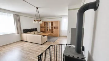 Gemütliches Wohnzimmer mit Kaminofen und Laminatboden, ideal für kalte Tage.