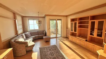 Helles Wohnzimmer mit Holzvertäfelung, Parkettboden und Zugang zum Balkon.