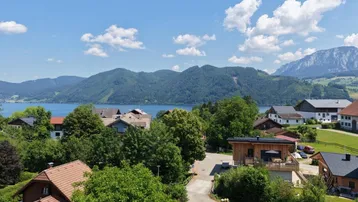 Panoramablick auf den See und die umliegende Berglandschaft mit Häusern.