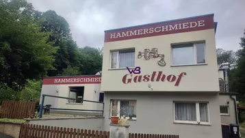 Gebäude der Hammerschmiede Gasthof mit schlichter Fassade und umgebender Natur.