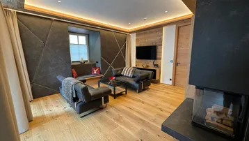 Modernes Wohnzimmer im alpinen Stil mit Kamin, Holzboden und gemütlicher Sitzecke.