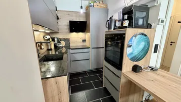 Moderne Küche mit dunklen Fliesen, integrierten Geräten und einer praktischen Arbeitsfläche.