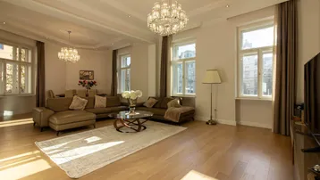 Helles und geräumiges Wohn-Esszimmer mit eleganten Kronleuchtern, Parkettboden und großen Fenstern.