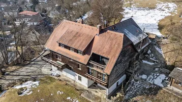 Luftaufnahme des Anwesens mit traditionellem Haus und umliegender, teilweise schneebedeckter Landschaft.