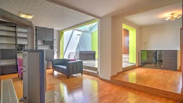 Helles, mehrstufiges Wohnzimmer mit Holzboden, Kaminofen und großen Dachfenstern für viel Tageslicht.