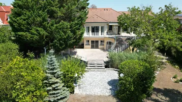 Großzügiges Anwesen mit weitläufigem Garten, großer Terrasse und Blick auf das Gebäude.