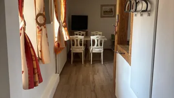 Heller Flur mit Holzboden und Blick in den Essbereich, gekennzeichnet durch einen rustikalen Holzbalken.